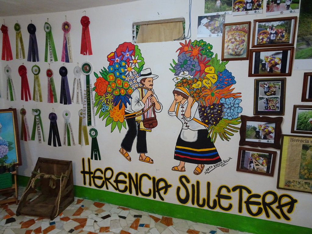 Изображение на "silleteros", ферма за цветя в Санта Елена. Всяко лято в Меделин се провежда фестивала Feria de las Flores, по време на който производителите дефилират по улиците носещи на гърбовете си типичните "silletas".